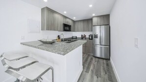 Eine moderne Küche mit einer Granit Arbeitsplatte, Edelstahlgeräten und Holzschränken.