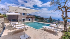 Un espace aménagé au bord de la piscine, avec des chaises longues et un grand parasol, offrant une vue panoramique.