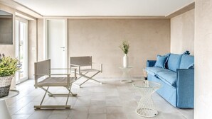 Un salon moderne comprenant un canapé, deux fauteuils, une table basse et une plante.