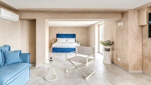 Une chambre à coucher moderne avec un lit, un canapé bleu, une chaise blanche et une petite table.