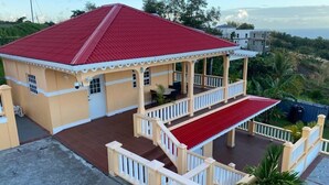 A two-story building with a red roof and a covered balcony area. - Dalys Luxury Apartments (Choppins)