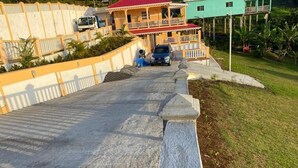 A residential area with a paved driveway leading to a house with a red roof and a balcony. - Dalys Luxury Apartments (Choppins)