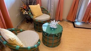 A room with wicker chairs and a round table, a vase with flowers, and curtains. - Dalys Luxury Apartments (Choppins)