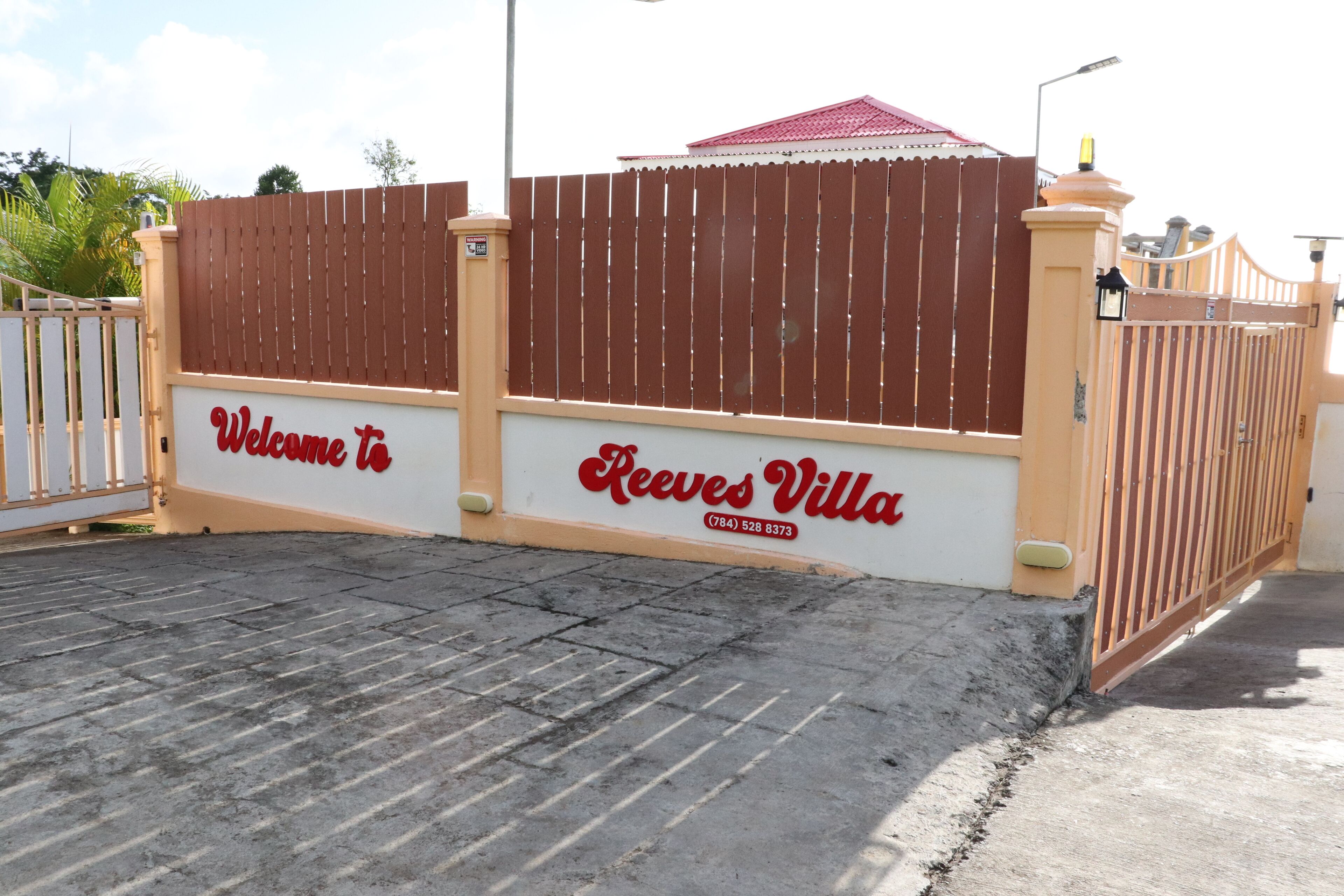 A gated entrance with a sign reading "Welcome to Reeves Villa" and a contact number.