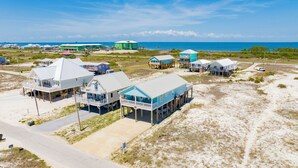 A coastal area with multiple beachfront properties, including houses with balconies and decks, some elevated on stilts, and a large building with a green roof. - Gulf Views | Private Pool | Pet Friendly | Beach Access (Gulf Shores)