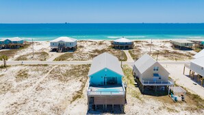 A beachfront property with multiple houses on stilts, a swimming pool, and a clear view of the ocean. - Gulf Views | Private Pool | Pet Friendly | Beach Access (Gulf Shores)