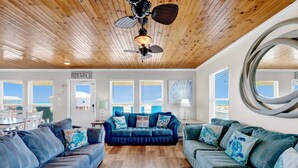 A room with a wooden ceiling, a blue sofa set, a round mirror, and a ceiling fan. - Gulf Views | Private Pool | Pet Friendly | Beach Access (Gulf Shores)