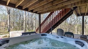 Un jacuzzi con una terraza de madera y una escalera que lleva a una zona cubierta.