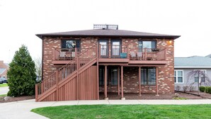 A two-story brick house with a balcony on the upper floor, a staircase leading to the entrance, and a small front yard with a tree. - Dual Townhomes in Central Downtown Huron (Huron)