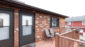 A brick exterior with two doors, a small porch with a railing, and a pair of chairs. - Dual Townhomes in Central Downtown Huron (Huron)