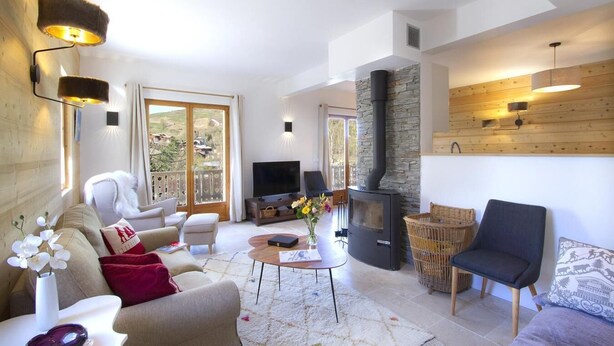 A spacious living room with a stone fireplace, comfortable seating, a flat-screen TV, and a large window offering a view of the outdoors. - 200m from ski slopes, floor -2, terrace, fireplace or stove, parking, tv, ski locker, 80m² (Les Deux Alpes)