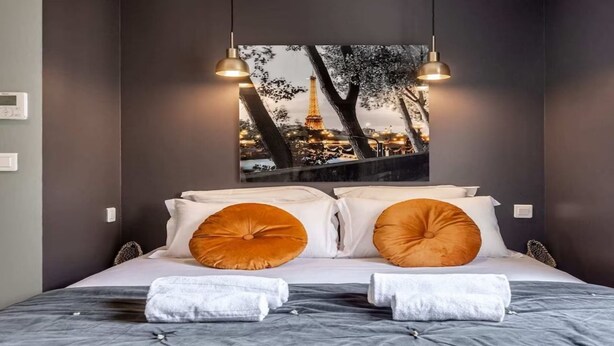 A hotel room with a bed, two large pillows, a view of the Eiffel Tower, and two pendant lights. - Nestled along the Que banks of Seine -perfection in intimate luxury near Louvre (Paris)