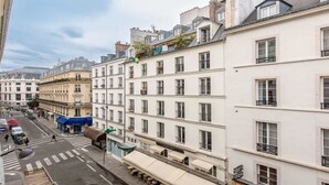 A street view of a European city with multi-story buildings, a café, and a crosswalk. - Nestled along the Que banks of Seine -perfection in intimate luxury near Louvre (Paris)