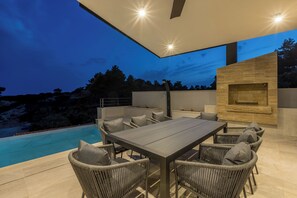 Un patio al aire libre con piscina, una mesa de comedor y sillas de mimbre.