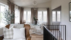 A room with a wicker chair, a glass table, and a potted plant. - Koselig Cottage: Charming 1950s Danish Cottage on 5 Acres (Ellison Bay)
