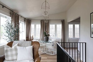 A room with a wicker chair, a glass table, and a potted plant.