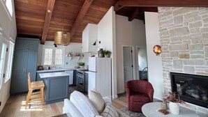 A spacious living area with a fireplace, a kitchen with a central island, and a dining area. - Koselig Cottage: Charming 1950s Danish Cottage on 5 Acres (Ellison Bay)