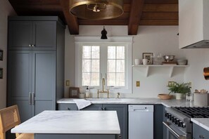 A kitchen with a white countertop, a sink with gold fixtures, and a stove.