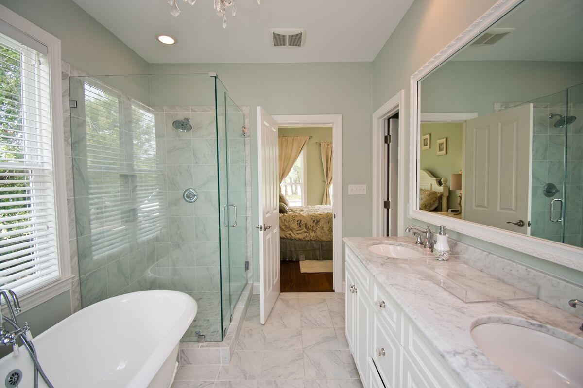 A bathroom with a glass-enclosed shower, a freestanding bathtub, and a vanity with a large mirror.