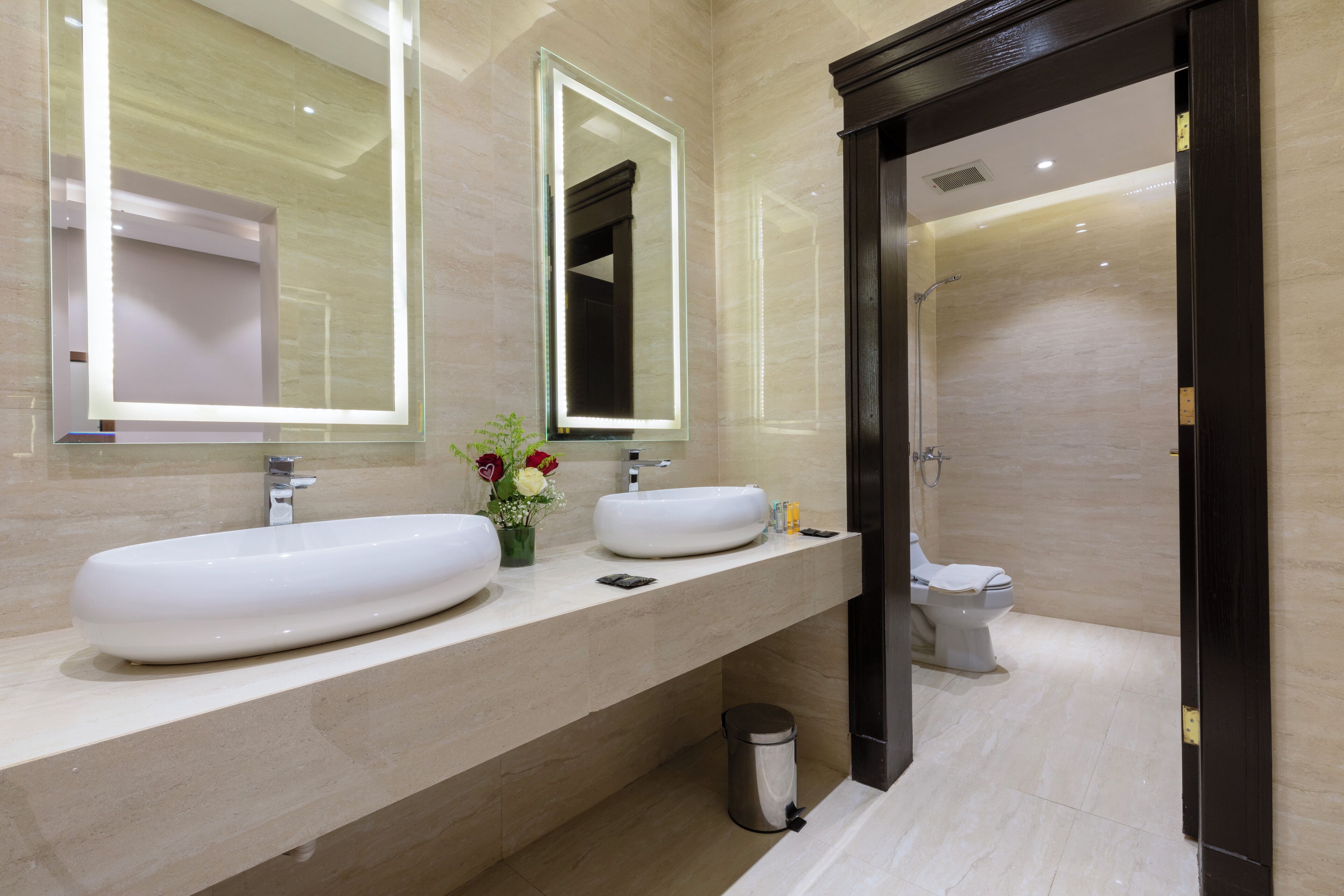 A modern bathroom with two large sinks, a mirror, and a toilet.