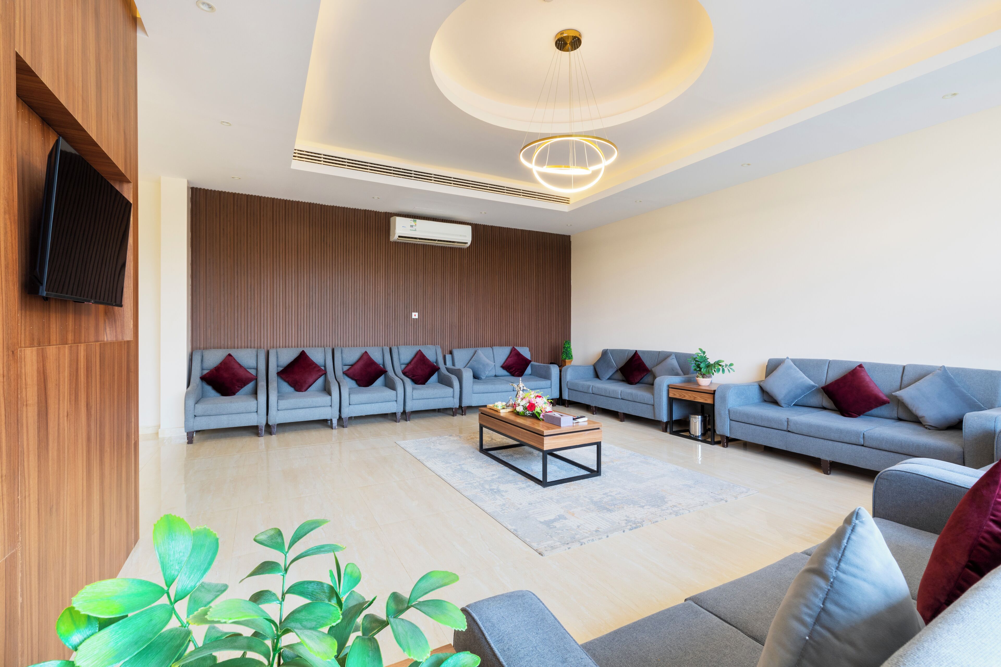 A modern living room with a sectional sofa, a coffee table, and a TV mounted on the wall.