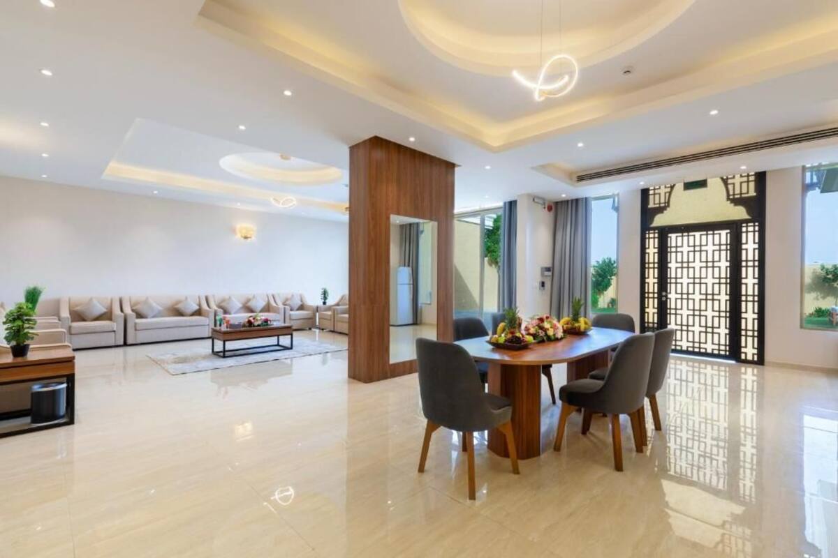 Un salon moderne comprenant un ensemble de canapés, une table basse et un coin repas avec une table et des chaises en bois.