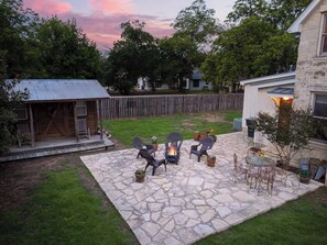 Une terrasse en pierre avec des meubles d’extérieur, un foyer et un petit espace jardin.