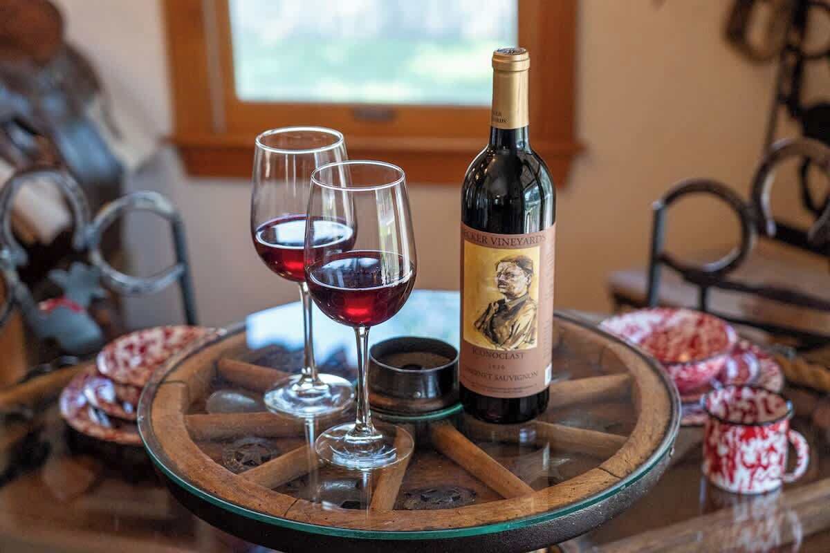 Uma garrafa de vinho com copos sobre uma mesa de madeira.