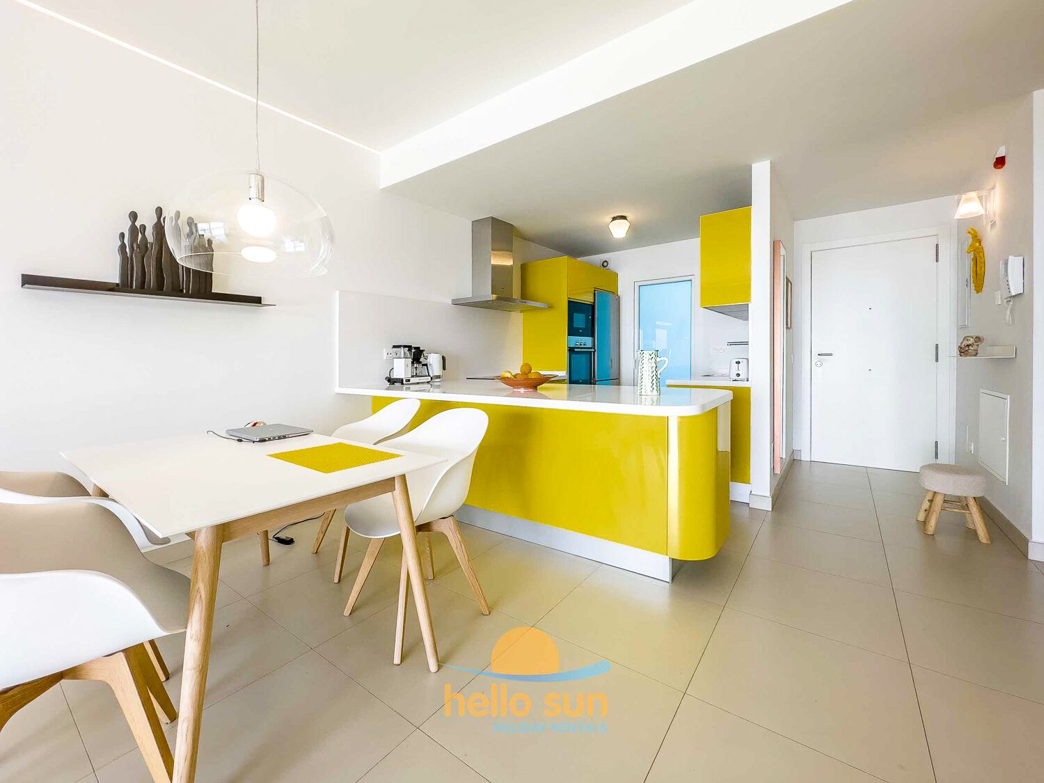 A modern kitchen with a yellow island, white cabinetry, and a dining area with a white table and chairs.