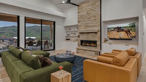 Una sala de estar moderna con chimenea, ventanas amplias y un televisor.