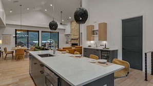 Una cocina moderna con una isla grande, suelo de madera y chimenea de piedra.