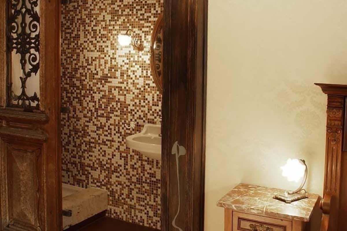 A bathroom with mosaic tile walls, a wooden cabinet, and a hanging light fixture.