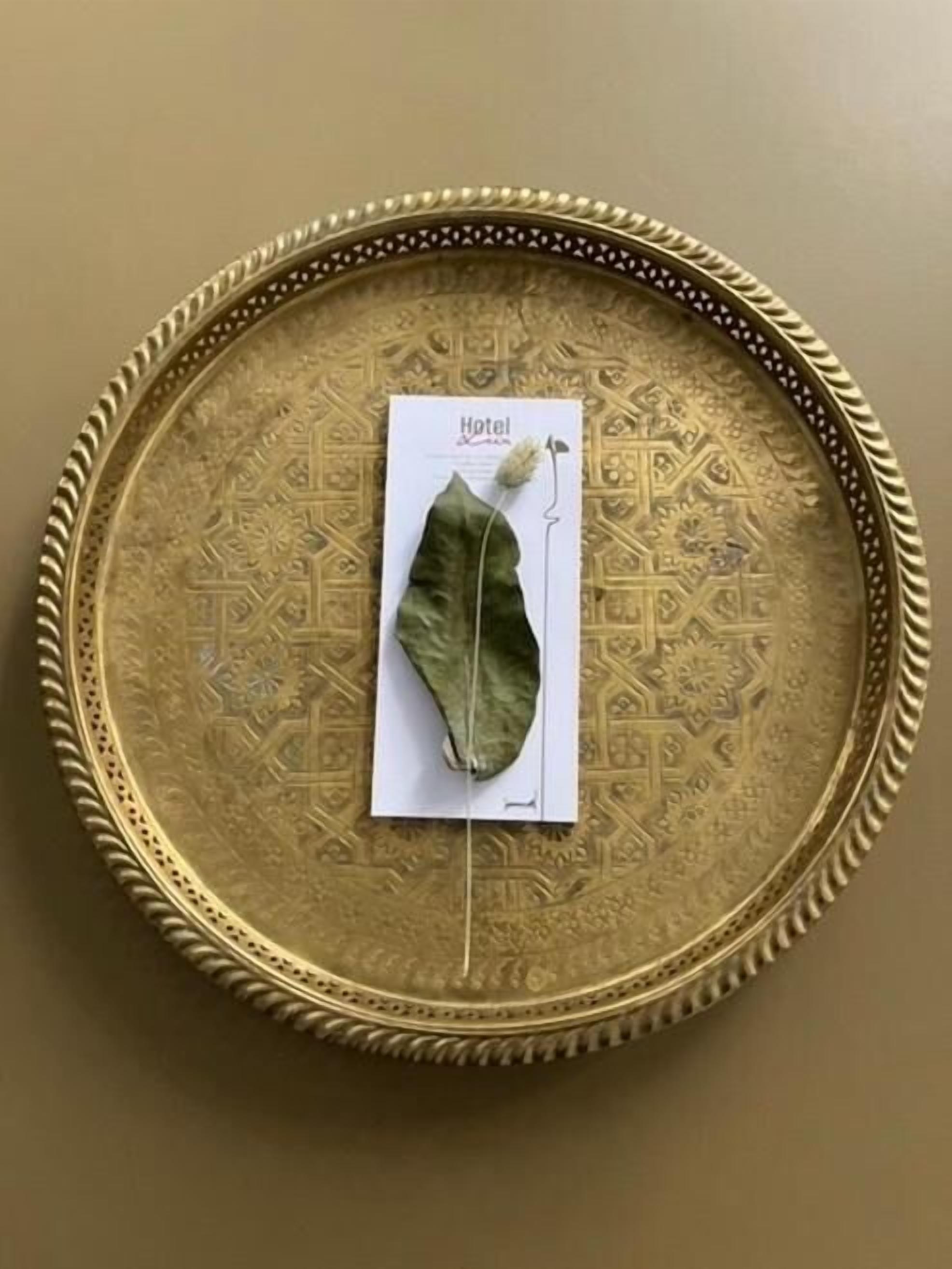 A decorative tray with intricate patterns and a single leaf placed on top of a card labeled "Hotel."