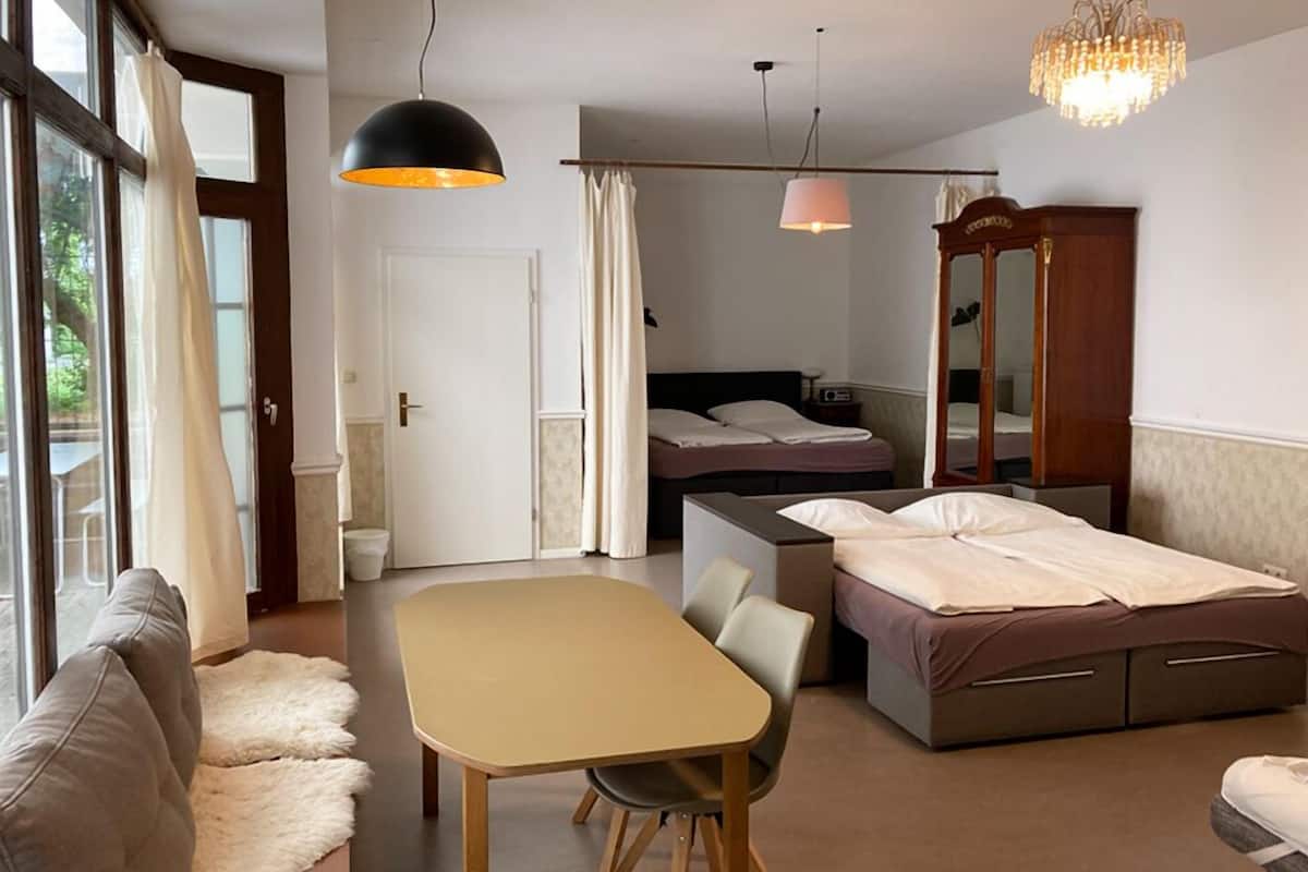 A modern room with a bed, a desk, a chair, a sofa, and a dining table.
