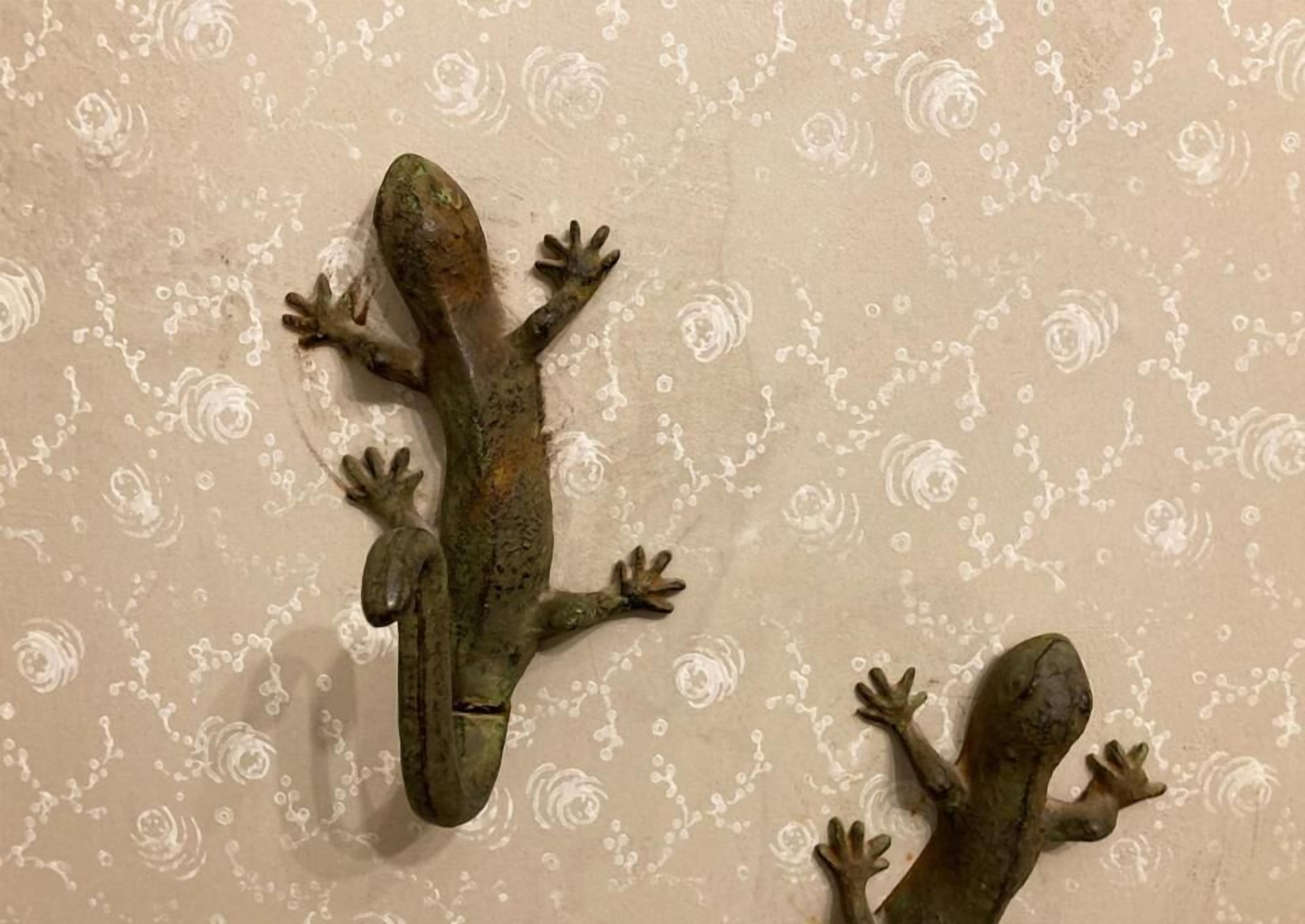 Two reptile wall decorations on a patterned wall.