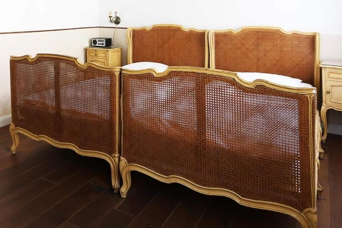 A traditional four-poster bed with a woven headboard and footboard, a bedside table, and a radio.