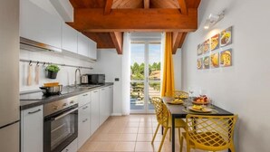 A modern kitchen with white cabinets, a wooden ceiling, and a dining area with yellow chairs.