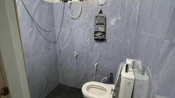 A small bathroom with a toilet, a shower, and a sink.