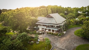 A large, single-story building with a sloped roof, surrounded by lush greenery and a winding driveway. - Hotel Bukit Indah Saumlaki by LeGreen (Saumlaki)