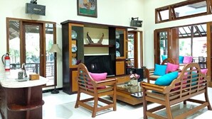 A living room with wooden furniture, a television, and a bookshelf. - Hotel Bukit Indah Saumlaki by LeGreen (Saumlaki)