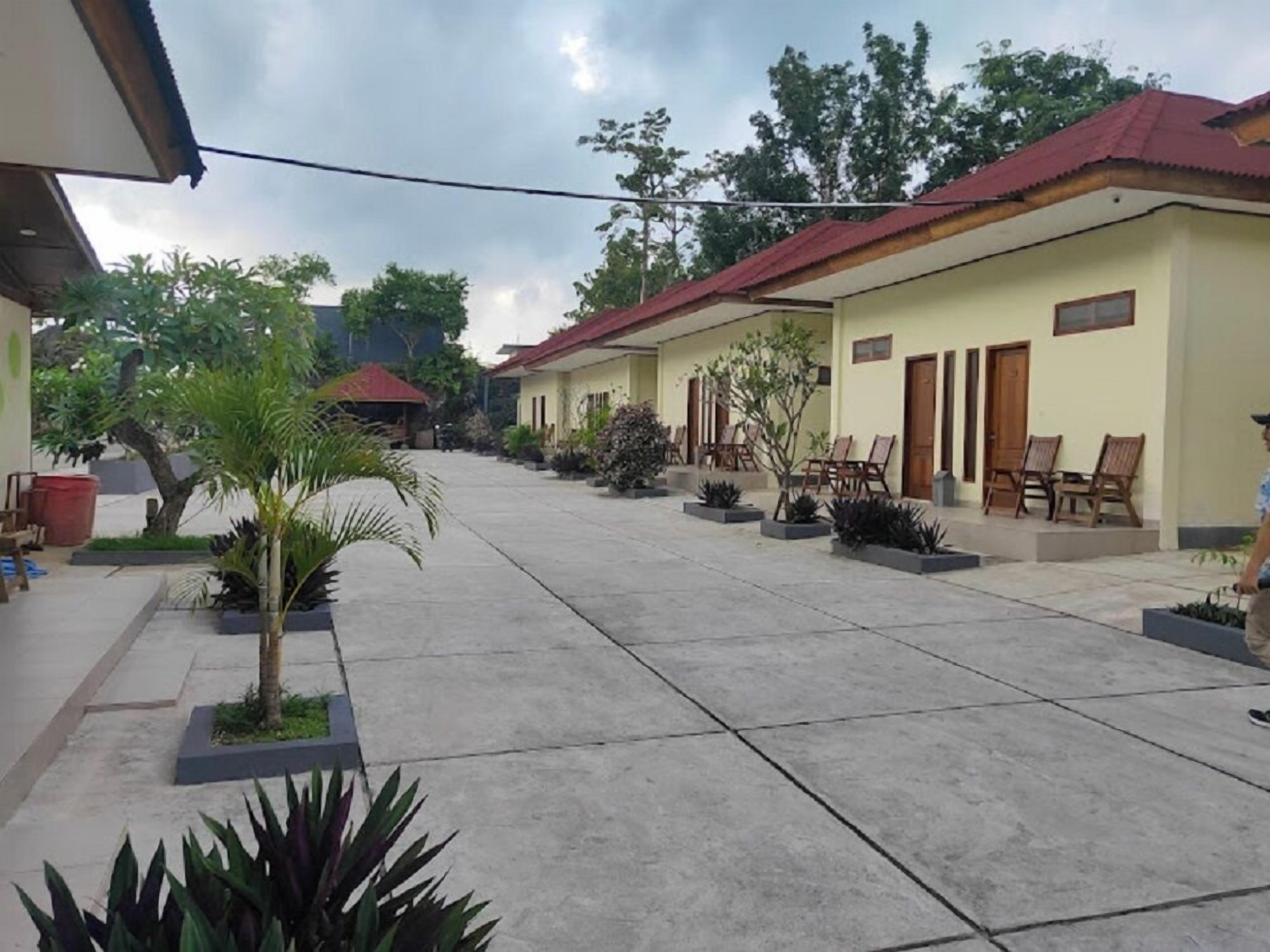 A courtyard with a paved walkway, several potted plants, and outdoor seating areas.
