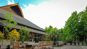 A covered outdoor seating area with wooden furniture and a tiled floor. - Hotel Bukit Indah Saumlaki by LeGreen (Saumlaki)