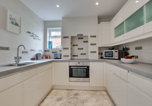 Enjoy cooking in this well-lit kitchen with a central island, oven, and stainless steel sink.