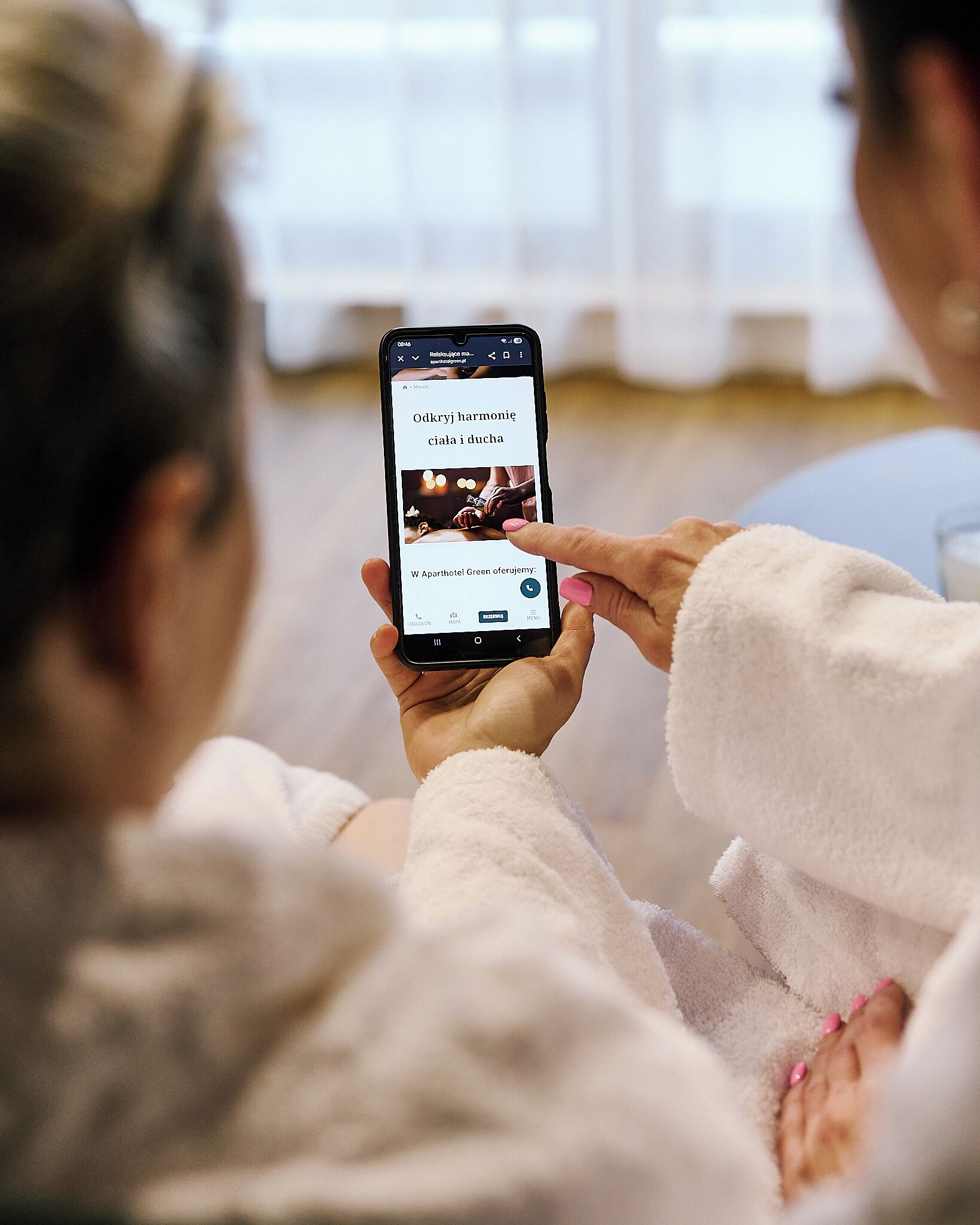 Una persona sosteniendo un teléfono inteligente que muestra una página de reserva de hotel.