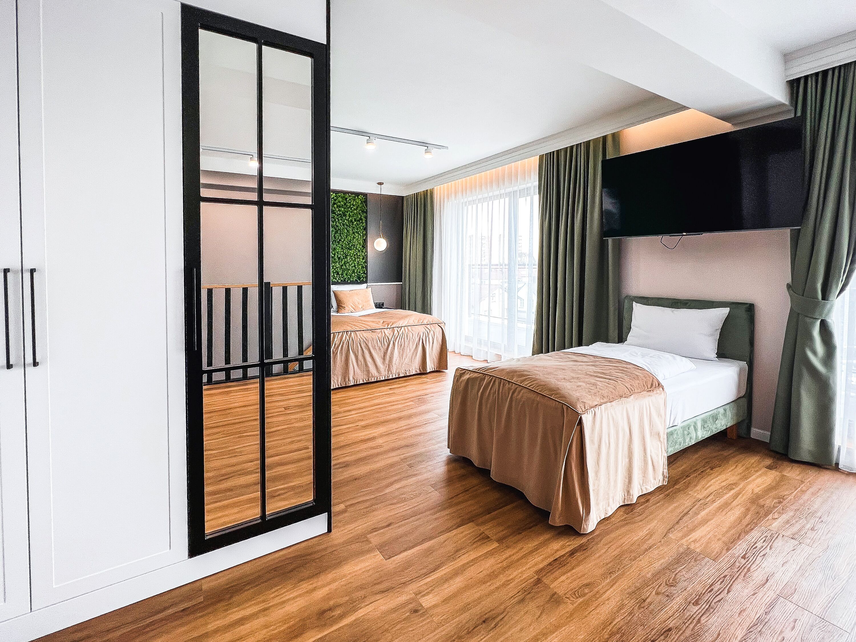 Ett hotellrum med två sängar, en stor garderob, en grön vägg och utsikt över staden.