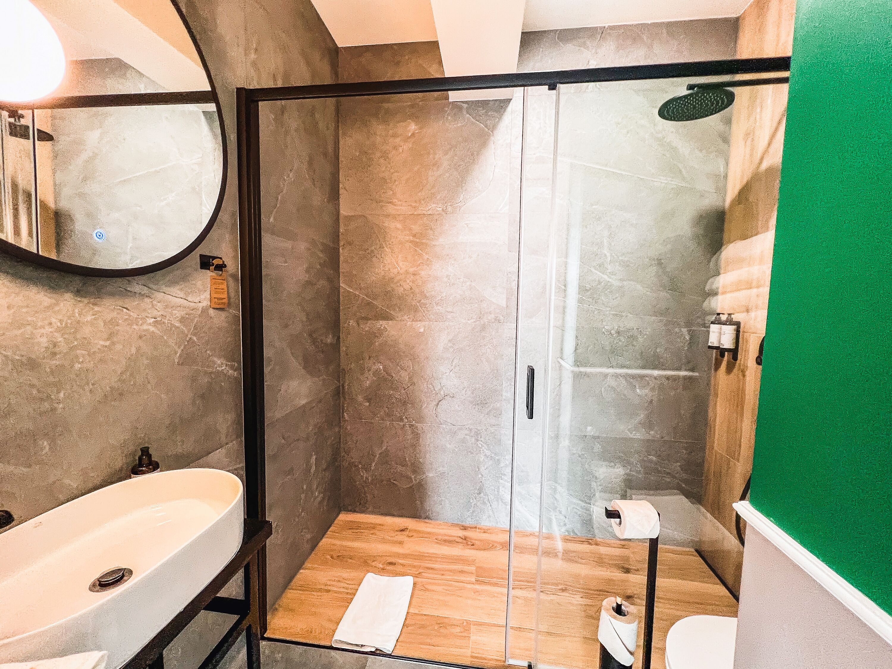 A modern bathroom with a glass-enclosed shower, a wooden vanity, and a large mirror.