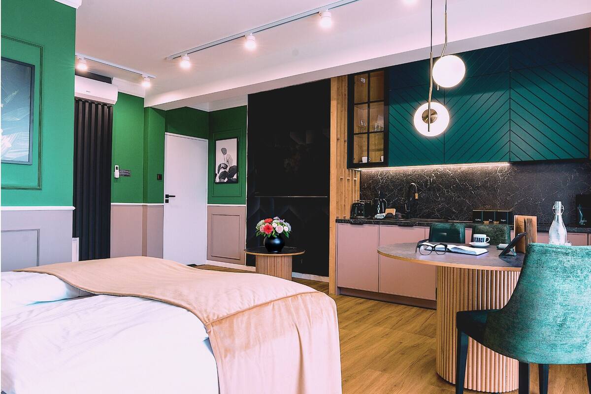 Una habitación de hotel moderna con una cama, un pequeño comedor, una cocina y un baño.