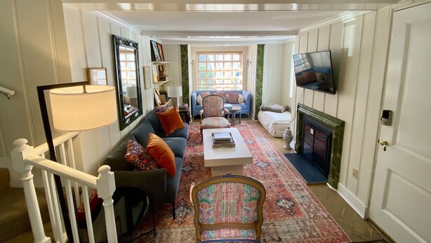A living room with a sofa, armchairs, a coffee table, a fireplace, and a TV mounted on the wall. - Historic 4-Bedroom Home in the Heart of Newport (Newport)