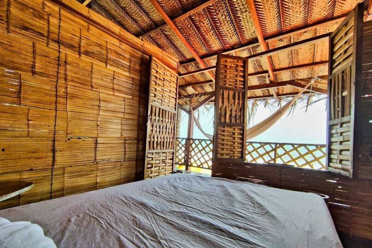 A room with a bed, wooden walls, and a thatched roof.