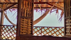 A room with a bed, a woven ceiling, and a view of the beach. - Hostal HALALIKU (Santa Marta)